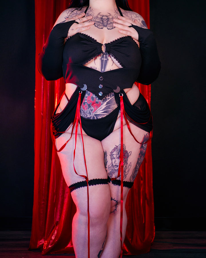 Moonlit Ritual Witch Lingerie by MOEFLAVOR. A mystical black lingerie set with adjustable underwear, moon pendants draped in red ribbons, and long mesh gloves, creating a seductive, witchy vibe